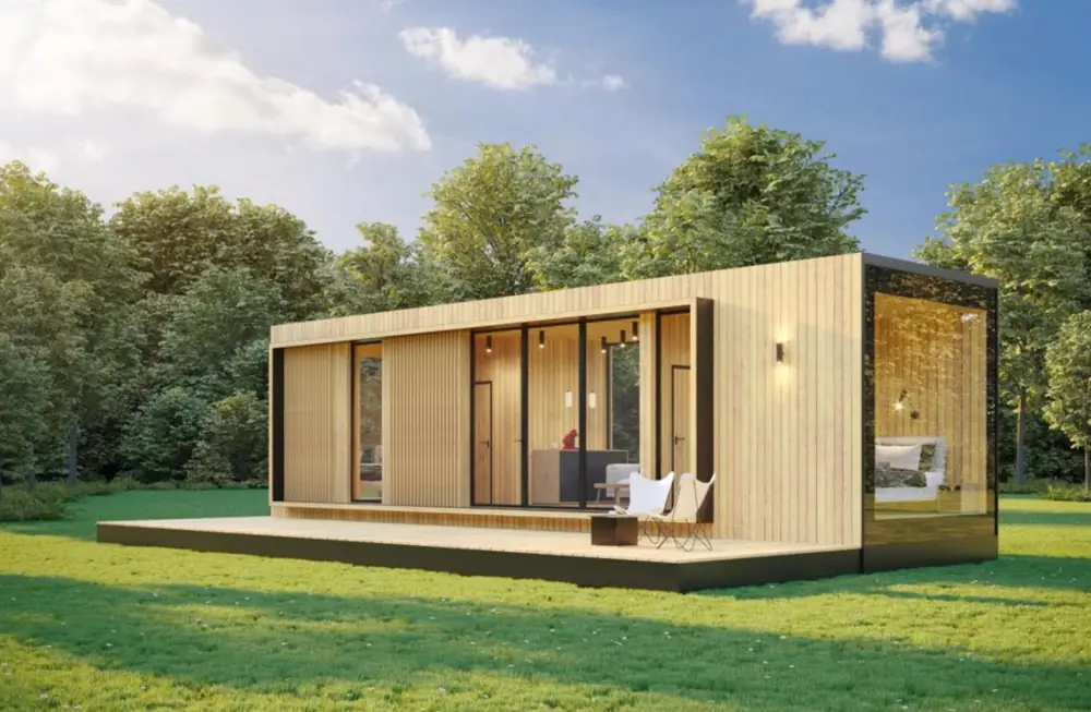 Holzverkleidetes Tiny House mit breiter Fensterfront und zwei weißen Gartenstühlen